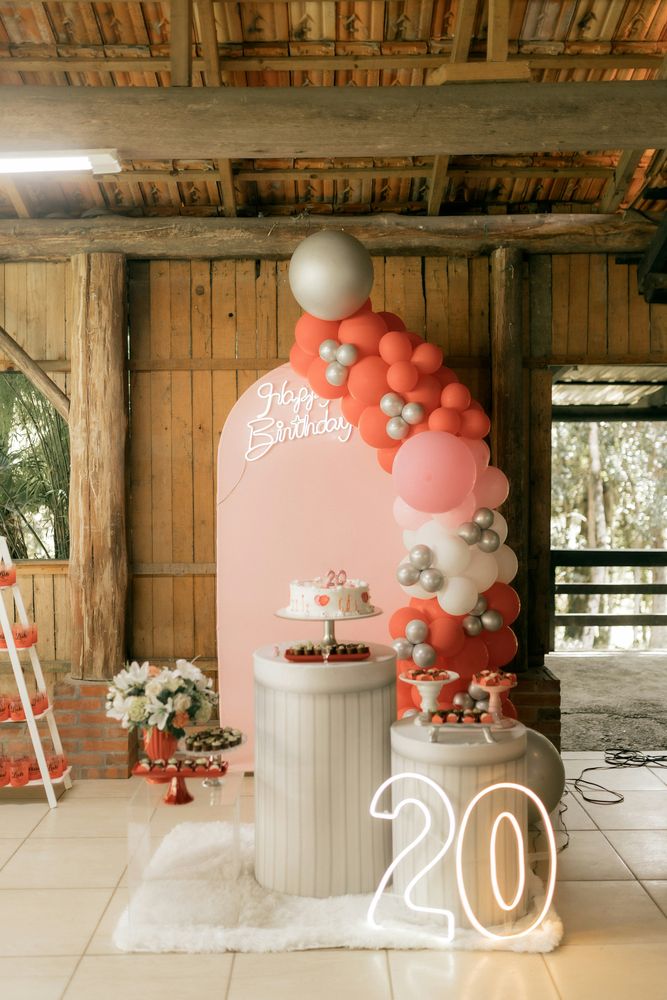 A coral and white balloon arch over a dessert display