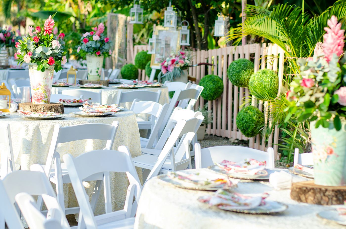A garden party with white chairs and pink floral centerpieces
