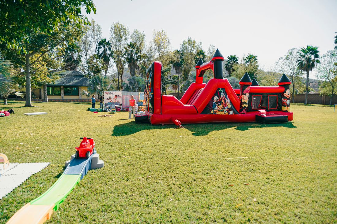 A red bounce house and toddler play area on a lawn